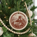 A Christmas tree decorated with ornaments, including a circular ornament featuring a castle and a winding path.