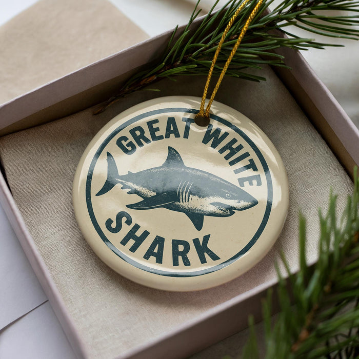 A circular ornament with the text "GREAT WHITE SHARK" and a graphic of a shark is displayed in a box, surrounded by pine branches.