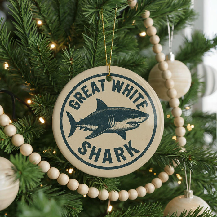 A Christmas tree decorated with ornaments, including a large circular ornament with a shark image and the text "GREAT WHITE SHARK" on it.