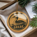 A circular ornament with a duck image and the word "GREBE" printed on it, hanging from a string.