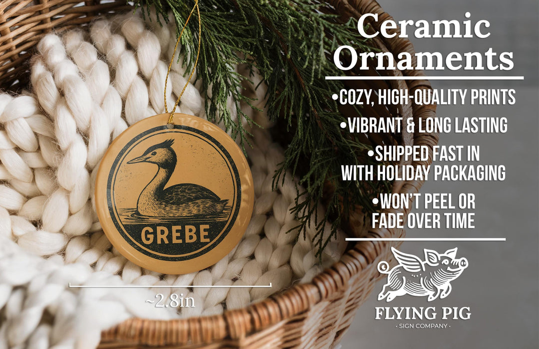 Ceramic ornaments, featuring a ceramic bird ornament with the word "GREBE" on it, are displayed in a wicker basket.
