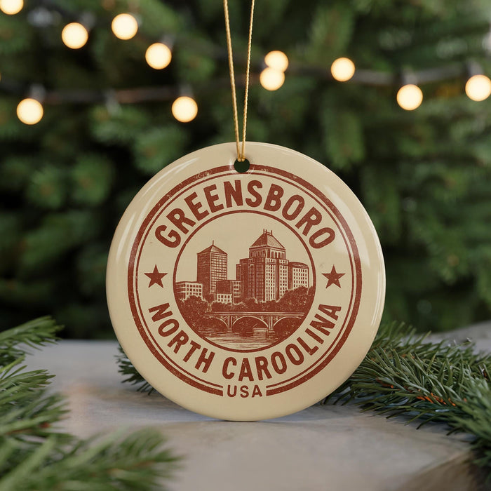 A circular ornament with the text "GREENSBORO NORTH CAROLINA USA" printed on it, hanging from a string.