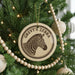 A circular ornament with a zebra's head on it, hanging from a Christmas tree.