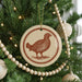 A Christmas tree decorated with ornaments, including a circular ornament featuring a bird design.