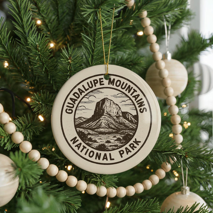 A Christmas tree decorated with ornaments, including a circular ornament with the text "GUADALUPE MOUNTAINS NATIONAL PARK" and a mountain illustration.