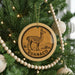 A Christmas tree decorated with ornaments, including a circular ornament with a llama image and the word "GUANACO" written on it.