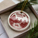 A decorative ornament in a box, featuring a red and white design with mountains and a boat, and the text "GUILIN CHINA".