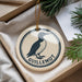 A decorative ornament featuring a black and white illustration of a bird, with the text "GUILLLEMOT" printed on it, is displayed in a box with pine branches.