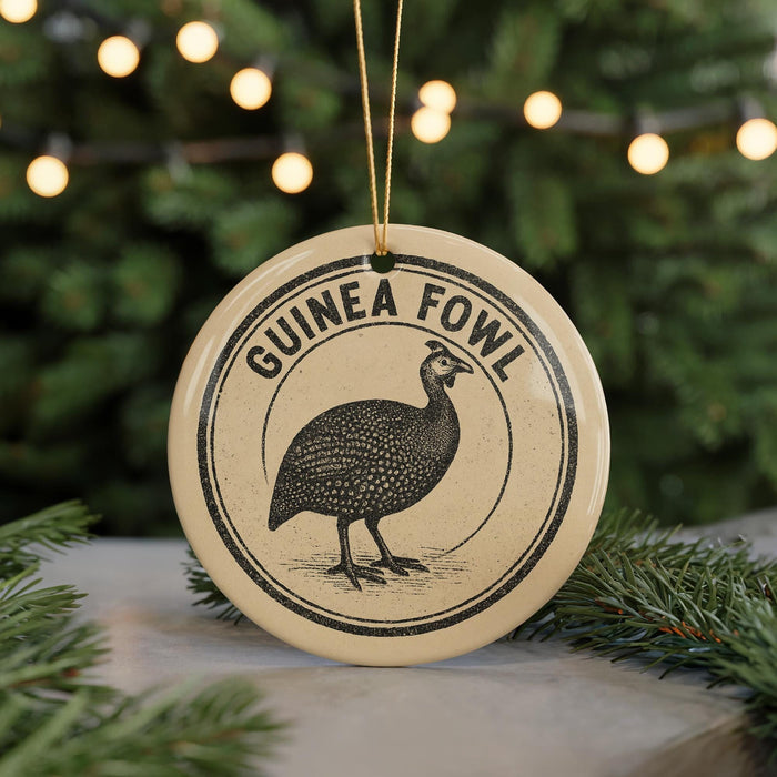 A round ornament with the text "GUINEA FOWL" and an illustration of a guinea fowl is displayed on a Christmas tree.