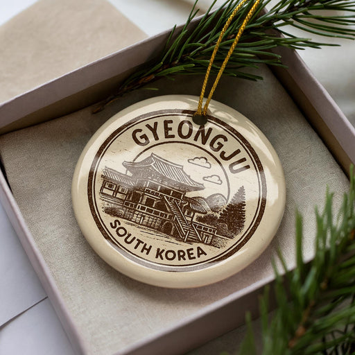 A decorative ornament in a box, featuring a circular design with a temple and the text "GYEONGJU SOUTH KOREA".