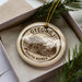 A decorative ornament in a box, featuring a circular design with a temple and the text "GYEONGJU SOUTH KOREA".