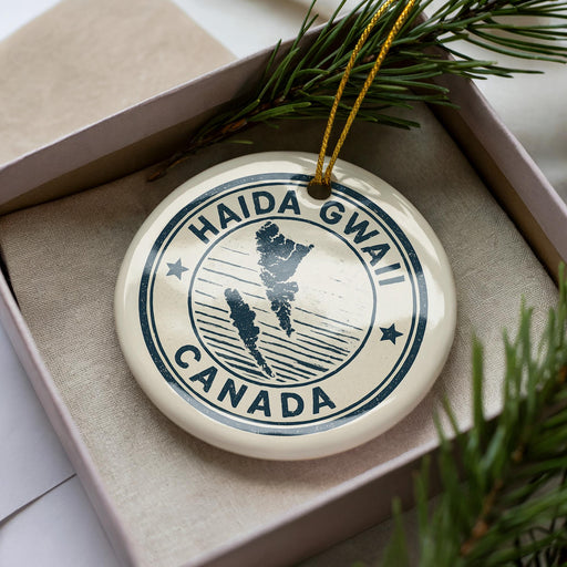 A circular ornament with the text "HAIDA GWAI CANADA" printed on it, surrounded by pine branches.