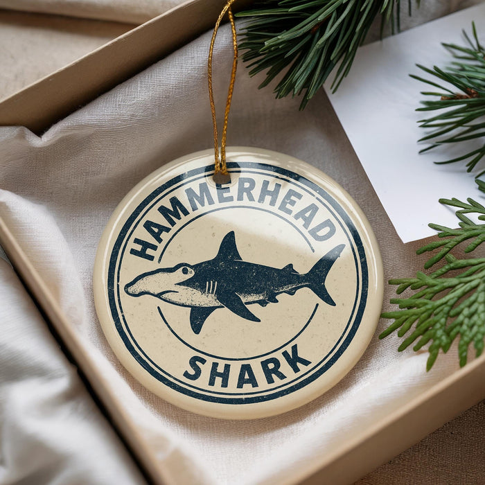 A round ornament with a hammerhead shark design and the text "HAMMERHEAD SHARK" is displayed in a box with pine branches.