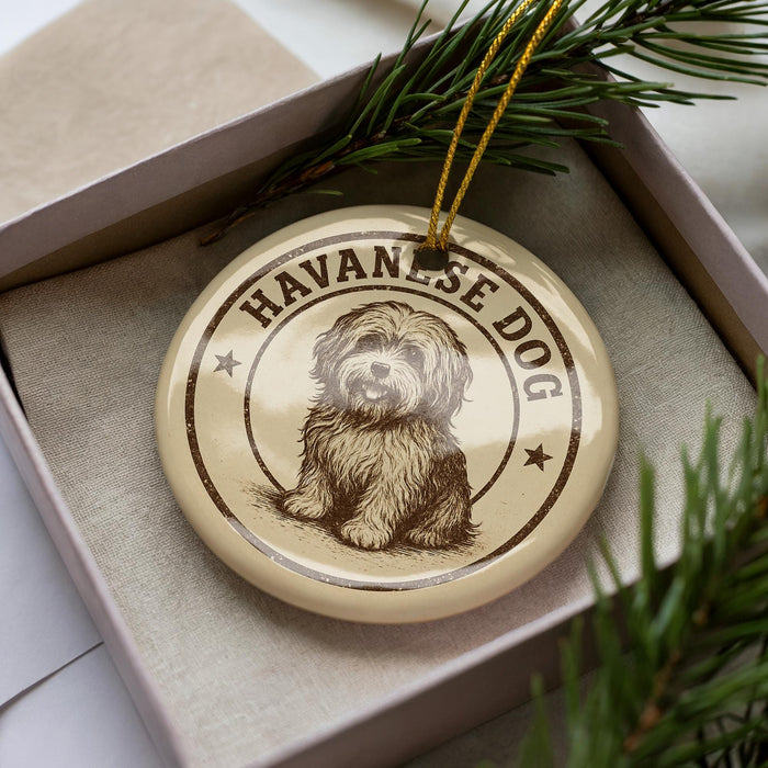 A round ornament with a dog image and the text "Havanese Dog" on it, placed in a box with pine branches.