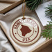 A circular ornament with the text "HAWAII'ISLAND USA" printed on it, surrounded by pine branches.