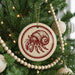 A Christmas tree decorated with ornaments, including a circular ornament featuring a red and white crab design.