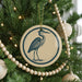 A Christmas tree decorated with ornaments, including a circular ornament featuring a blue heron.