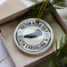 A white ornament with a blue border and a graphic of Hilton Head Island, surrounded by pine branches.