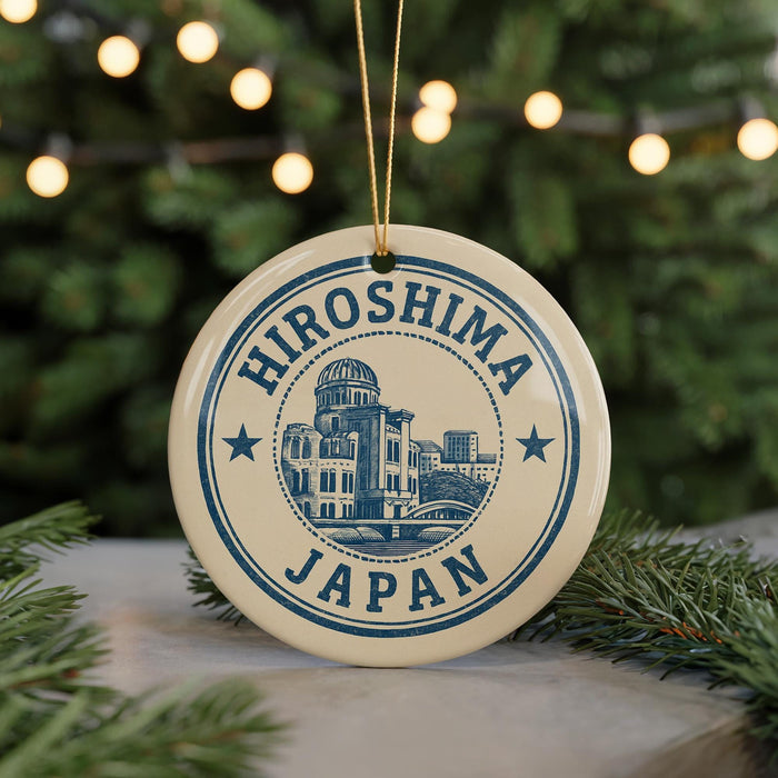 A circular ornament with the text "HIOSHIIMA JAPAN" and an illustration of a building, placed on a surface with pine branches in the background.