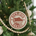A circular ornament on a Christmas tree with the text "HAWAII" in red and white, featuring a mountain and beach scene.