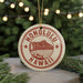 A circular ornament with the text "HONOLULU HAWAII" printed on it, featuring a mountain and beach scene.