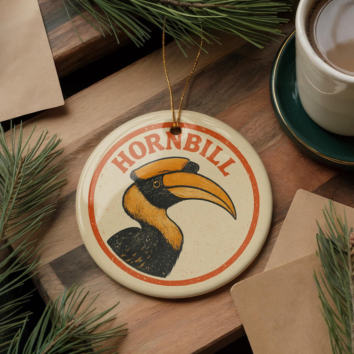 A hornbill ornament with the word "HORNBILL" is displayed on a wooden surface, surrounded by pine branches and a cup of coffee.