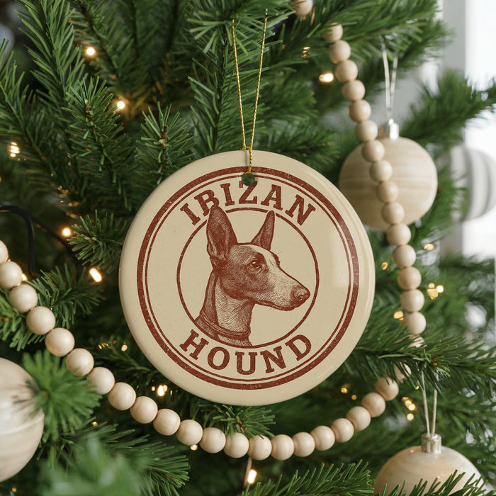 A Christmas tree decorated with ornaments, including a circular ornament with the text "IBIZAN HOUND" and a wooden bead decoration.