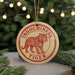 A round ornament with a tiger image and the text "INDOCHINESE TIGER" is displayed on a table, with a blurred background of a Christmas tree.