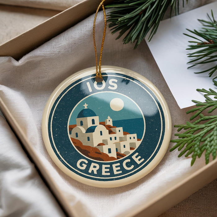A circular ornament with a design of a Greek island and buildings, featuring the text "IOS GREECE" on it.