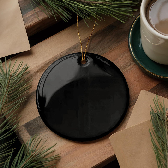 a black circular ornament, a cup of coffee, and some pine branches on a wooden surface.