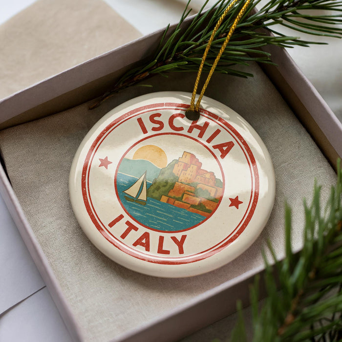 A decorative ornament in a box, featuring a sailboat and the text "ISCHIA ITALY" on a circular design.