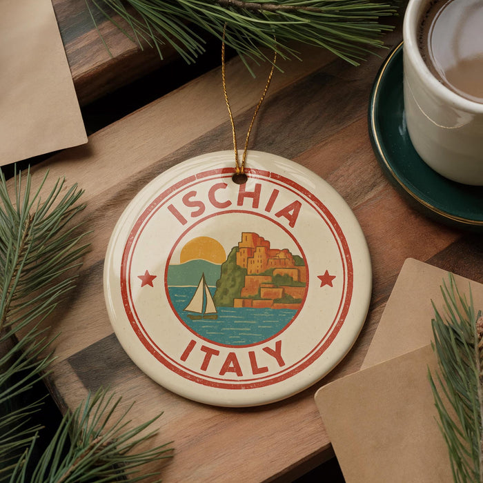 A circular ornament with the text "ISCHIA ITALY" and a graphic of a sailboat on a body of water, surrounded by pine branches and a cup of coffee on a wooden surface.