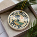 A circular ornament with the text "ISLA HOLBOX MEXICO" printed on it, surrounded by palm trees and a sunset.