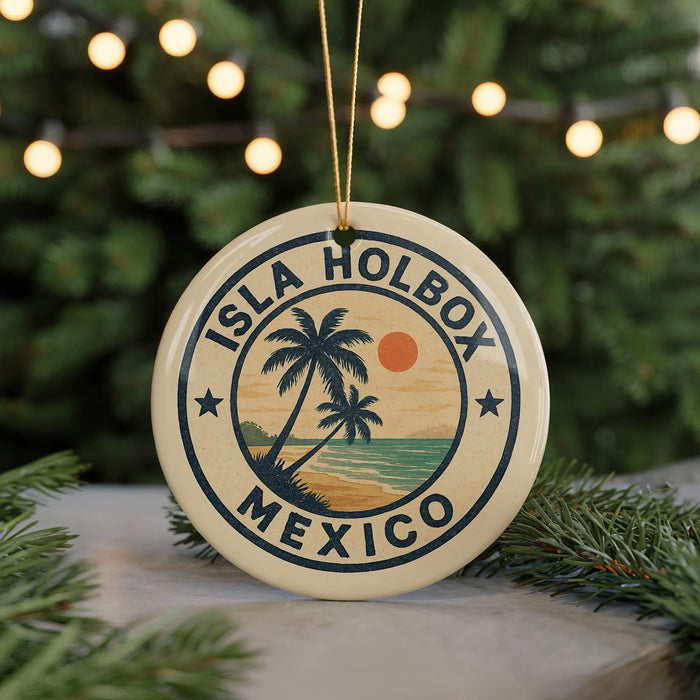 A circular ornament with the text "ISLA HOLBOX MEXICO" and a palm tree design, hanging from a string against a background of Christmas lights and greenery.