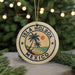 A circular ornament with the text "ISLA HOLBOX MEXICO" and a palm tree design, hanging from a string against a background of Christmas lights and greenery.