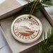 A circular ornament with the text "ISLA MARGARITA VENEZUELA" printed on it, surrounded by pine branches.