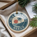 A circular ornament with the text "ISLA MÚJERES MEXICO" and a palm tree design, hanging from a string.