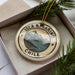 A circular ornament with the text "ISLA NAVARINO CHILE" printed on it, surrounded by a scenic landscape of mountains, trees, and a lake.