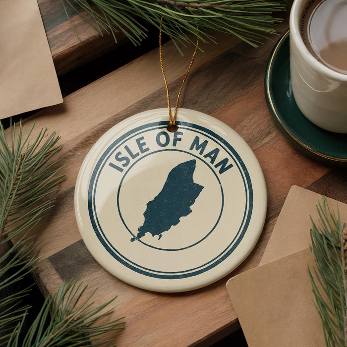 A circular ornament with the text "ISLE OF MAN" and a silhouette of the Isle of Man, a small island located in the English Channel between Great Britain and France, is displayed on a wooden surface.