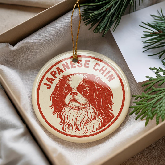 A round ornament with a red and white design featuring a dog's face, hanging from a string.
