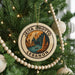 A Christmas tree decorated with ornaments, including a circular ornament with the text "JEITA GROTTO LEBANON" and a landscape illustration.