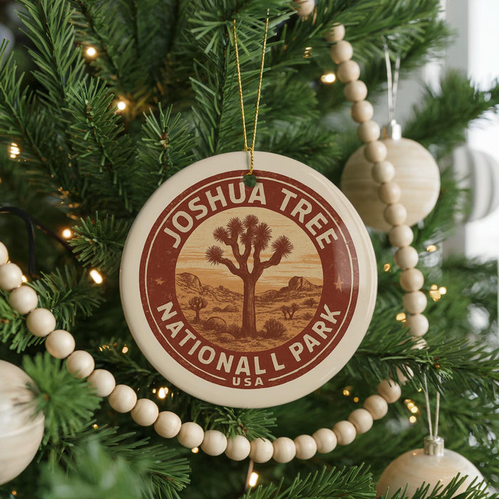A Christmas tree decorated with ornaments, including a circular ornament with the text "JOSUA TREE NATIONAL PARK USA" and a wooden bead decoration.