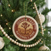 A Christmas tree decorated with ornaments, including a circular ornament with the text "JOSUA TREE NATIONAL PARK USA" and a wooden bead decoration.