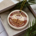 A circular ornament with the text "JOSUA TREE NATIONAL PARK USA" printed on it, surrounded by pine branches.