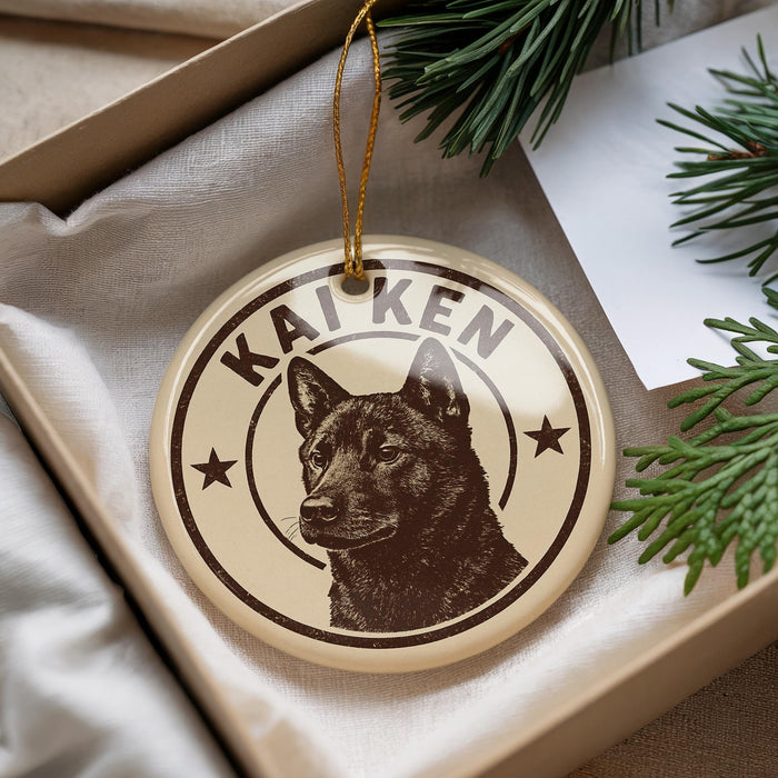 A circular ornament with a dog image and the name "KAIKEN" printed on it, placed in a box with pine branches.