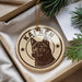 A circular ornament with a dog image and the name "KAIKEN" printed on it, placed in a box with pine branches.