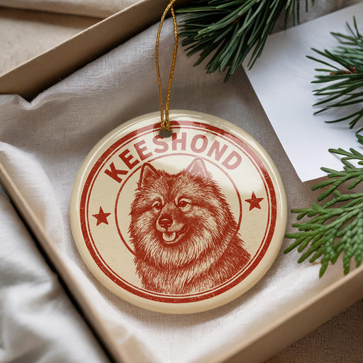 A round ornament with a picture of a dog's face and the word "Keeshond" written on it, hanging from a string.