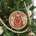 A Christmas tree decorated with ornaments, including a circular ornament with a red and white design featuring a dog's face and the word "Keeshond".