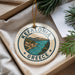 A decorative ornament with the text "KEFALONIA GREECE" and an illustration of a coastal town, surrounded by pine branches.