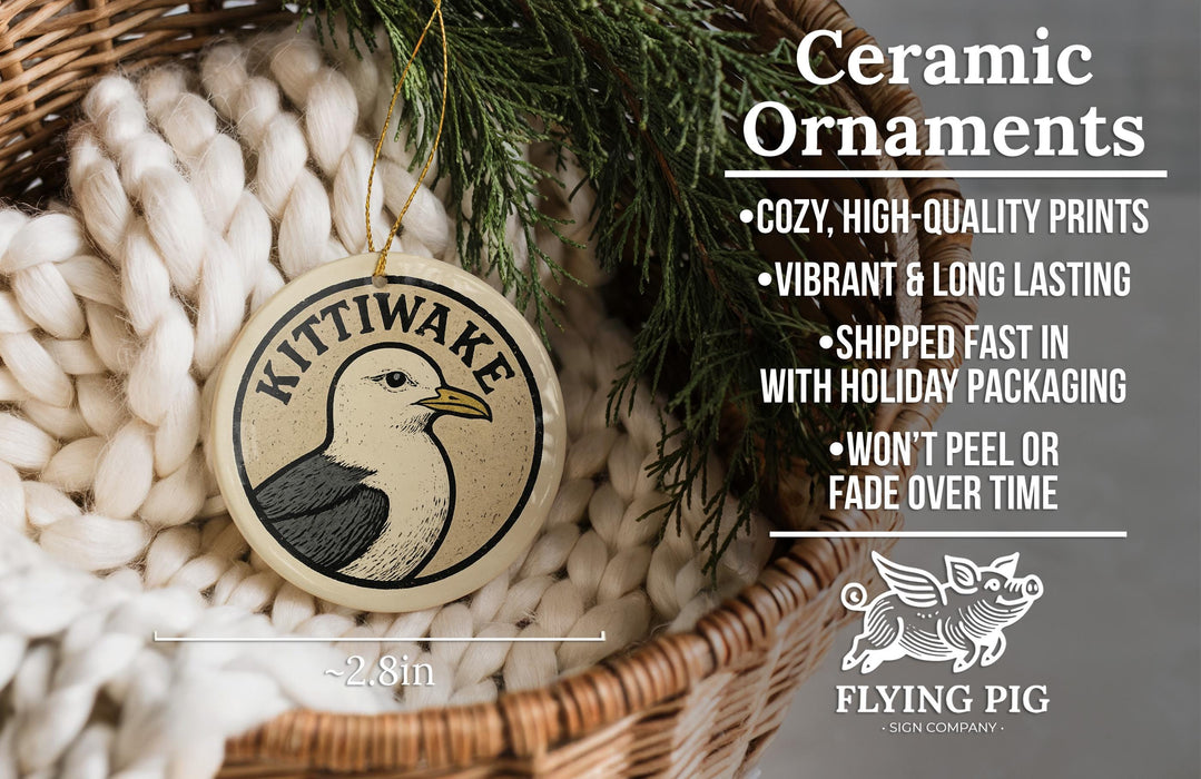 Ceramic ornaments, specifically a ceramic KITTiwake ornament, are displayed in a wicker basket. The ornament features a bird design and is described as a cozy, high-quality print, vibrant, and long-lasting. It is shipped fast in holiday packaging and does not peel or fade over time. The image also includes a scale for the ornament, indicating it is 2.8 inches in size.